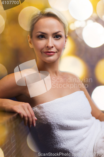 Image of beautiful young woman sitting in bath towel