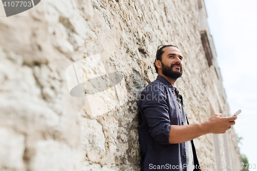 Image of man with smartphone at stone wall