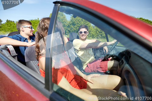 Image of happy friends driving in cabriolet car and talking