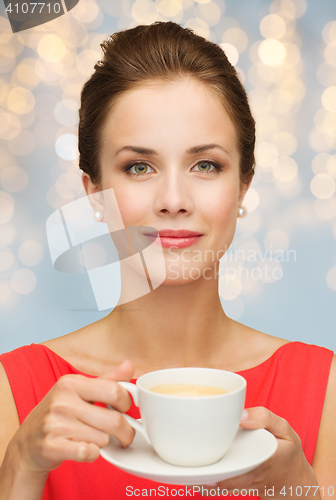 Image of woman in red with cup of coffee over lights