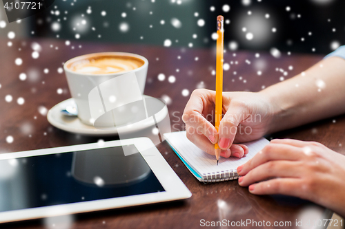 Image of woman with tablet pc writing to notebook