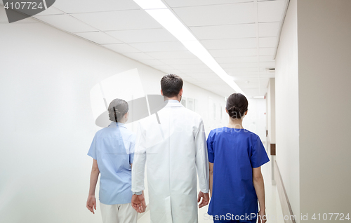 Image of group of medics or doctors walking along hospital