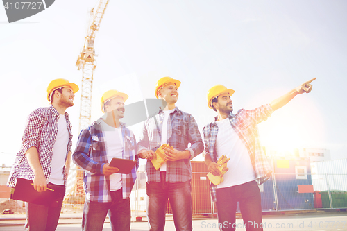 Image of group of smiling builders with tablet pc outdoors