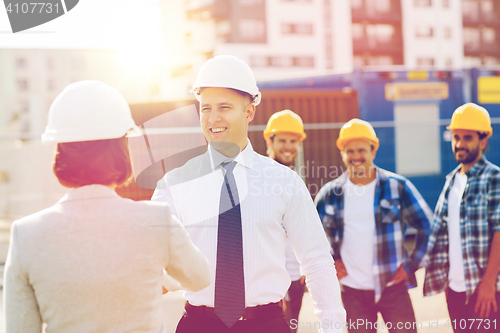 Image of group of smiling builders in hardhats outdoors