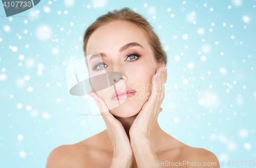Image of beautiful woman touching her face over snow