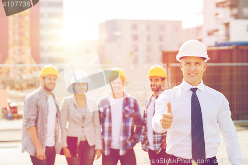 Image of group of smiling builders in hardhats outdoors