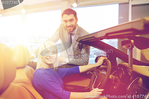 Image of happy couple buying car in auto show or salon