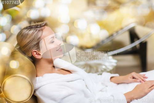 Image of beautiful young woman sitting in bath robe at spa