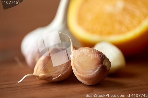 Image of close up of garlic and orange on wooden table