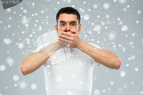 Image of man in white t-shirt covering his mouth with hands