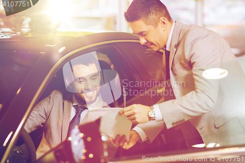 Image of happy man with car dealer in auto show or salon