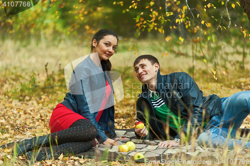 Image of Young romantic couple sits on plaid. Autumn picnic