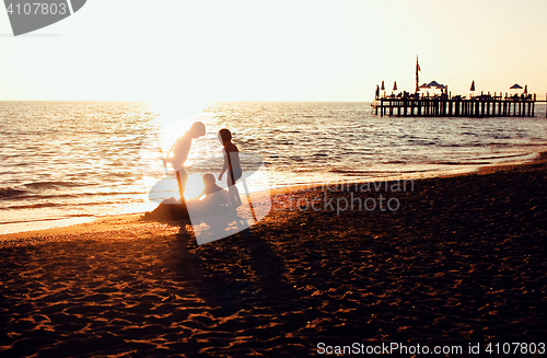 Image of lifestyle people concept: three little boys silhouette on sunset beach playing in water