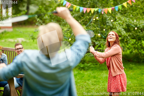 Image of happy friends playing badminton at summer garden