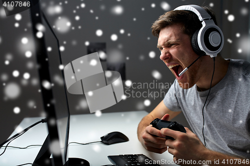 Image of man in headset playing computer video game at home