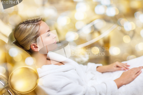 Image of beautiful young woman sitting in bath robe at spa