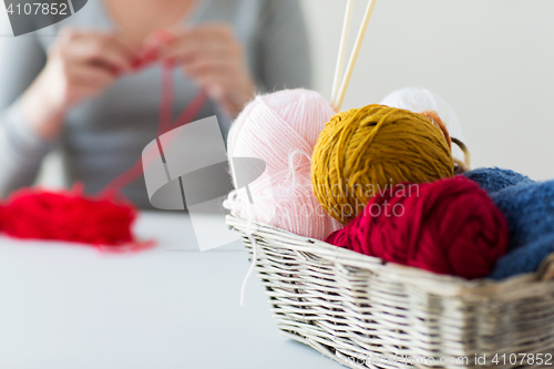 Image of woman, basket with knitting needles and yarn balls