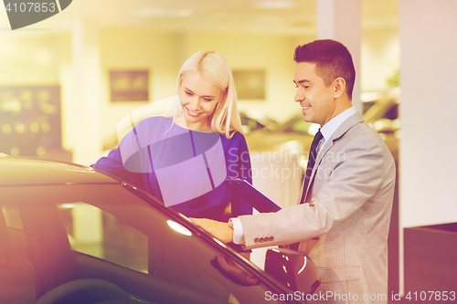 Image of happy woman with car dealer in auto show or salon