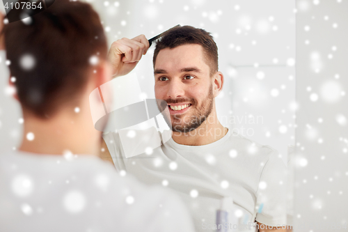 Image of happy man brushing hair with comb at bathroom