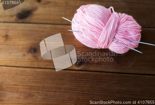 Image of knitting needles and ball of pink yarn on wood