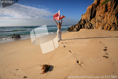 Image of A woman walks along the beach, travel, health and wellbeing