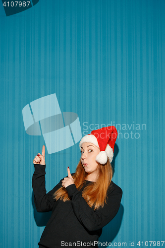 Image of Surprised christmas girl wearing a santa hat