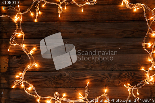 Image of Dark brown wooden background with shining garland on the frame