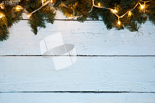 Image of Christmas holiday wooden background with fir tree and golden garland