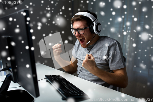 Image of man in headset playing computer video game at home