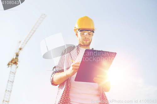 Image of builder in hardhat with clipboard outdoors