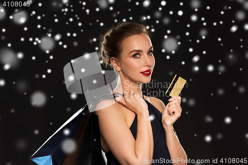 Image of woman with credit card and shopping bags over snow