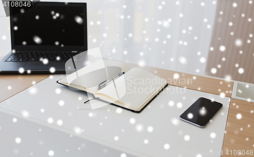 Image of notebook, laptop and smartphone on office table