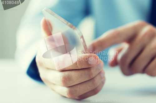 Image of close up of male hand with transparent smartphone