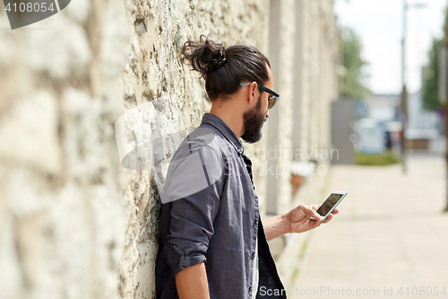 Image of close up of man with smartphone at stone wall