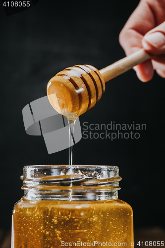 Image of Person dipping honey stick in 