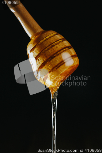 Image of Person dipping honey stick in