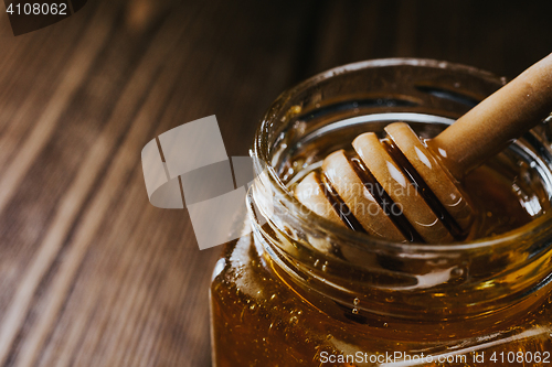 Image of Close up of honey stick in jar