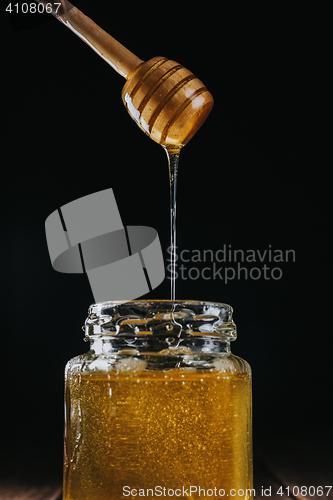 Image of Person dipping honey stick in