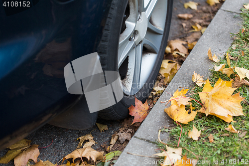 Image of close up of car wheel and autumn leaves