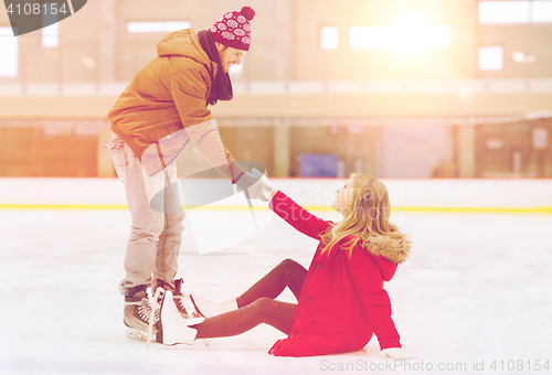 Image of man helping women to rise up on skating rink