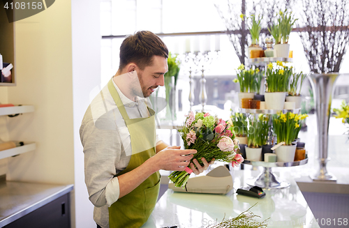 Image of smiling florist man making bunch at flower shop