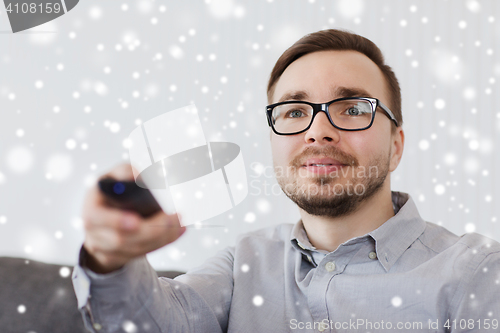 Image of smiling man with tv remote control at home