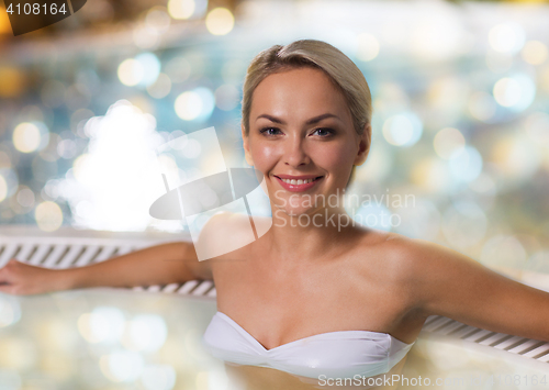 Image of happy woman sitting in jacuzzi at poolside