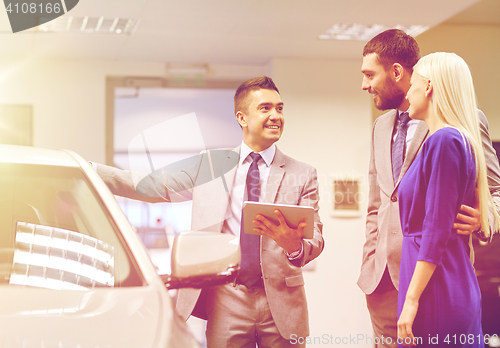 Image of happy couple with car dealer in auto show or salon