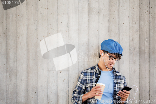 Image of man with earphones and smartphone drinking coffee