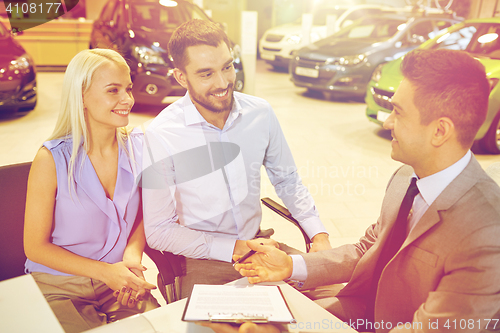 Image of happy couple with car dealer in auto show or salon