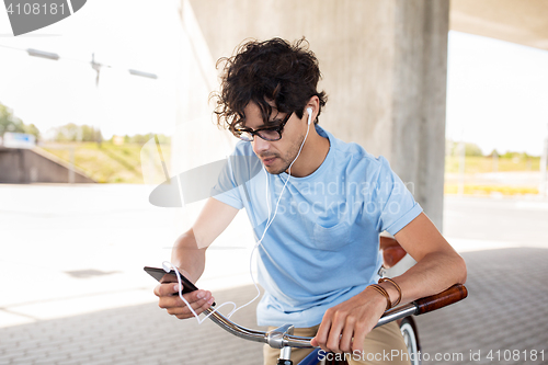 Image of man with smartphone and earphones on bicycle