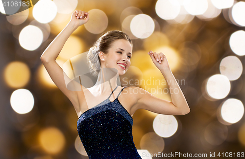 Image of happy woman dancing with raised hands over lights