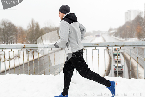 Image of man running along snow covered winter bridge road