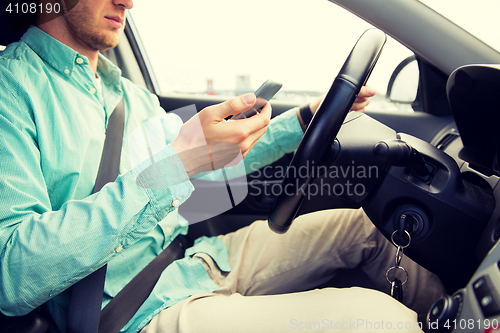 Image of close up of man with smartphone driving car